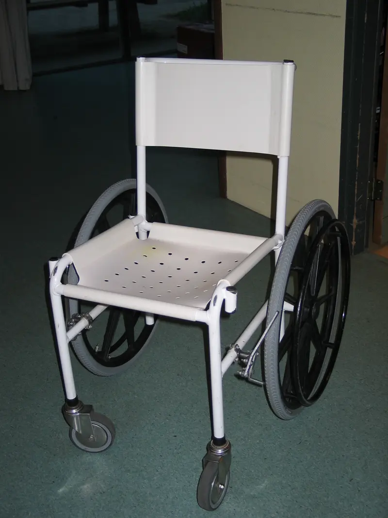 A white wheeled shower chair with a perforated seat and a backrest